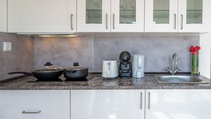 A modern kitchen with white cabinets, a granite countertop, a stove, a coffee maker, a toaster, and a sink. - Apartment with terrace in Estoril seaside villa (Estoril)