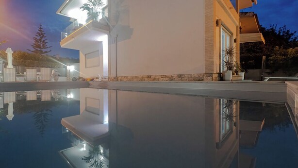 A modern house with a swimming pool, a balcony, and a well-lit exterior. - Apartment with terrace in Estoril seaside villa (Estoril)