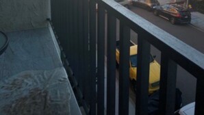 Un balcón con vista a una playa y un estacionamiento con coches.
