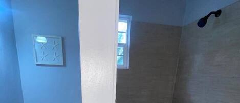 Un baño con inodoro, zona de ducha y una pequeña ventana.