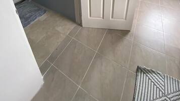A room with a white door, grey walls, and tiled flooring.