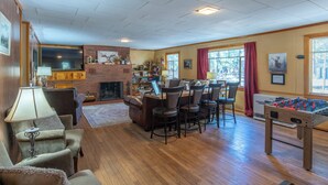 A cozy living room with a fireplace, a foosball table, and a bar area.