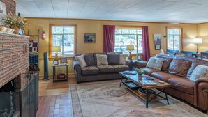 A living room with a fireplace, two couches, a coffee table, and a rug.