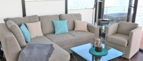 A modern living room with a grey sectional sofa, a small side table, and a glass coffee table.