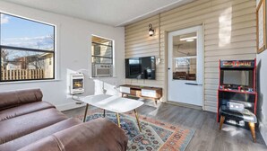 Una sala de estar con chimenea, televisor, sofá y consola de juegos.