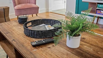 Una mesa de madera con una cesta tejida, un control remoto y una planta en maceta.