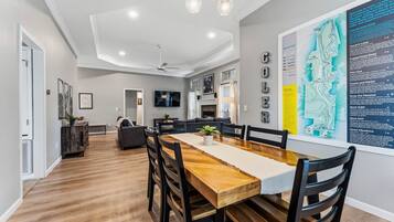 Un espace repas moderne avec une table et des chaises en bois, un ventilateur de plafond et une carte accrochée au mur.