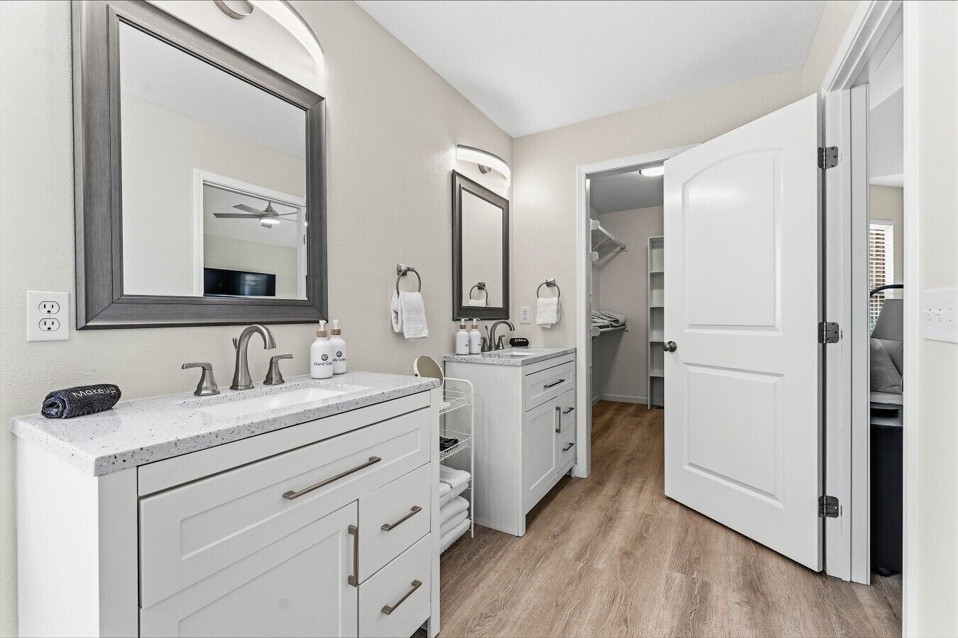 Un baño moderno con tocador doble, un espejo grande y un vestidor con puerta.