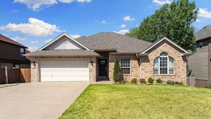 A single-story house with a garage, a front lawn, and a brick facade.