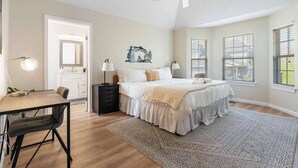 A bedroom with a bed, bedside tables, a desk, and a chair.