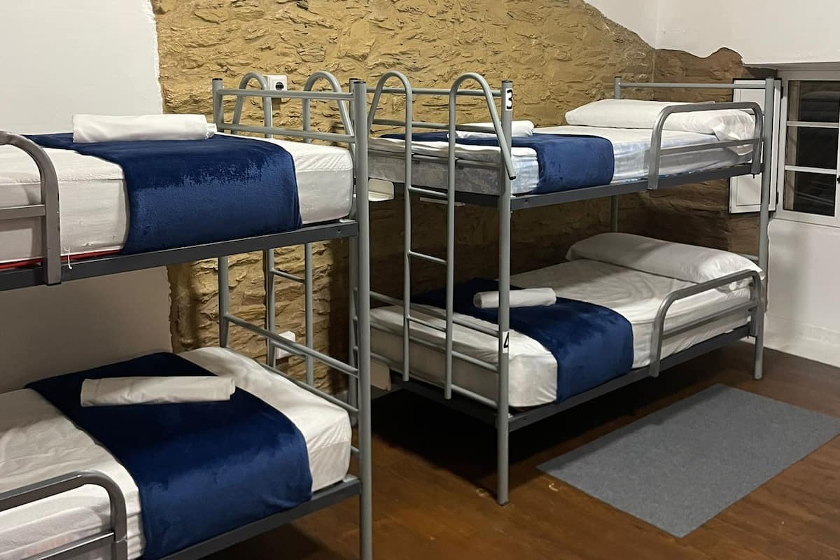 Bunk beds in a room with a stone wall and wooden ceiling.