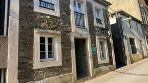 Edificio a due piani con facciata in pietra, diverse finestre e una porta ben visibile.