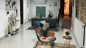 Un soggiorno moderno con un divano, una poltrona colorata, un tavolino da caffè e una libreria.
