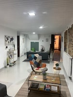 Una sala de estar moderna con un sofá, un sillón colorido, una mesa de centro y una estantería.
