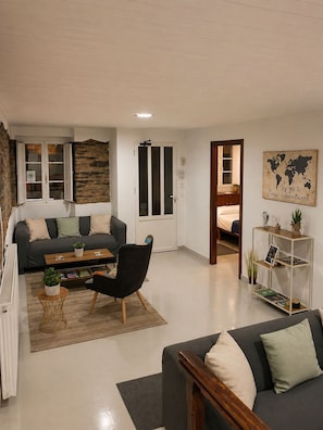 Una sala moderna con sofá, sillón, mesa de centro y estantería.
