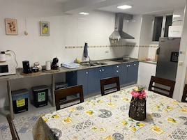 Una cocina con salpicadero de azulejos, extractor de acero inoxidable, refrigerador y una mesa de comedor con sillas.