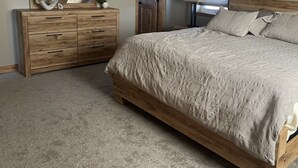 A bedroom with a wooden bed, a dresser, a mirror, and a ceiling fan.