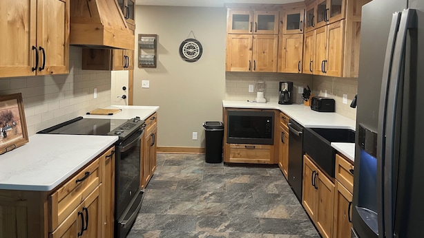 A kitchen with wooden cabinets, a white countertop, a black stove, a dishwasher, and a refrigerator.