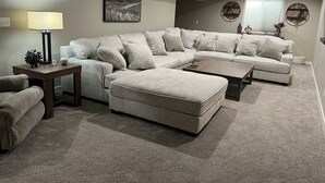 A modern living room with a sectional sofa, a coffee table, and a lamp.