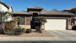 A residential house with a stone facade, a tiled roof, and a garage. - Lovely 3BR ranch home in Maricopa resort community w/ pools, courts, fitness ctr (Maricopa)