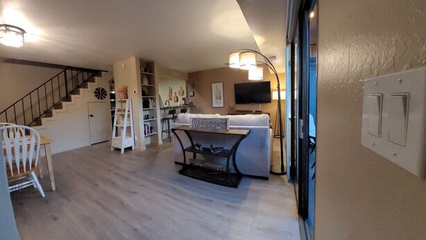 Un vaste espace de vie comprenant un escalier, un canapé blanc, une table basse et un téléviseur.