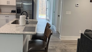 A modern kitchen with a central island, stainless steel appliances, and a view to the outdoors. - Modern new townhouse near Stone Mountain. Sleeps 10. (Snellville)