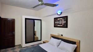 A bedroom with a bed, a ceiling fan, a door, and a framed picture on the wall. - Room-deluxe 2 Bedrooms Apartment In Coto (Cotonou)