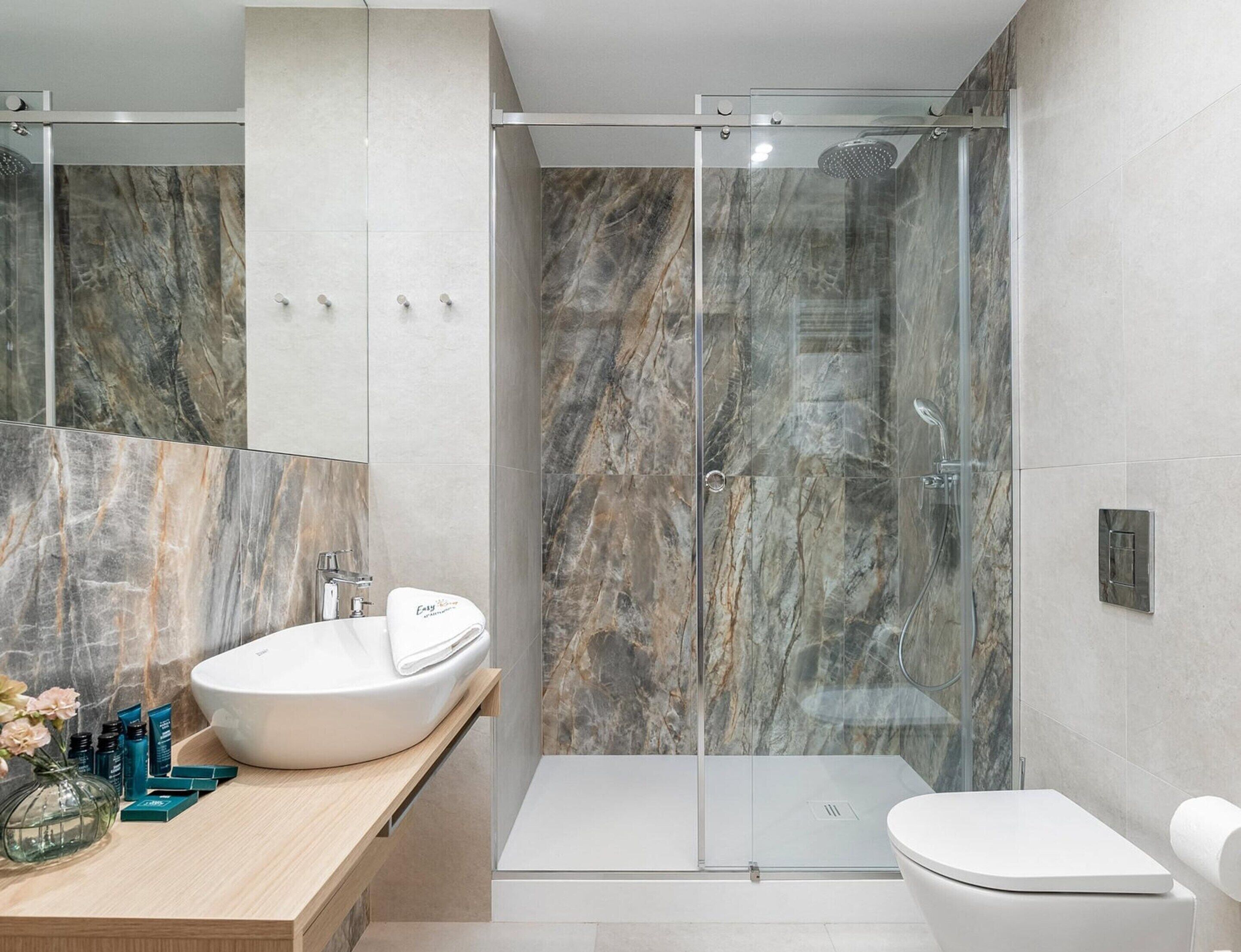 A modern bathroom with a glass-enclosed shower, a white sink, and a toilet.