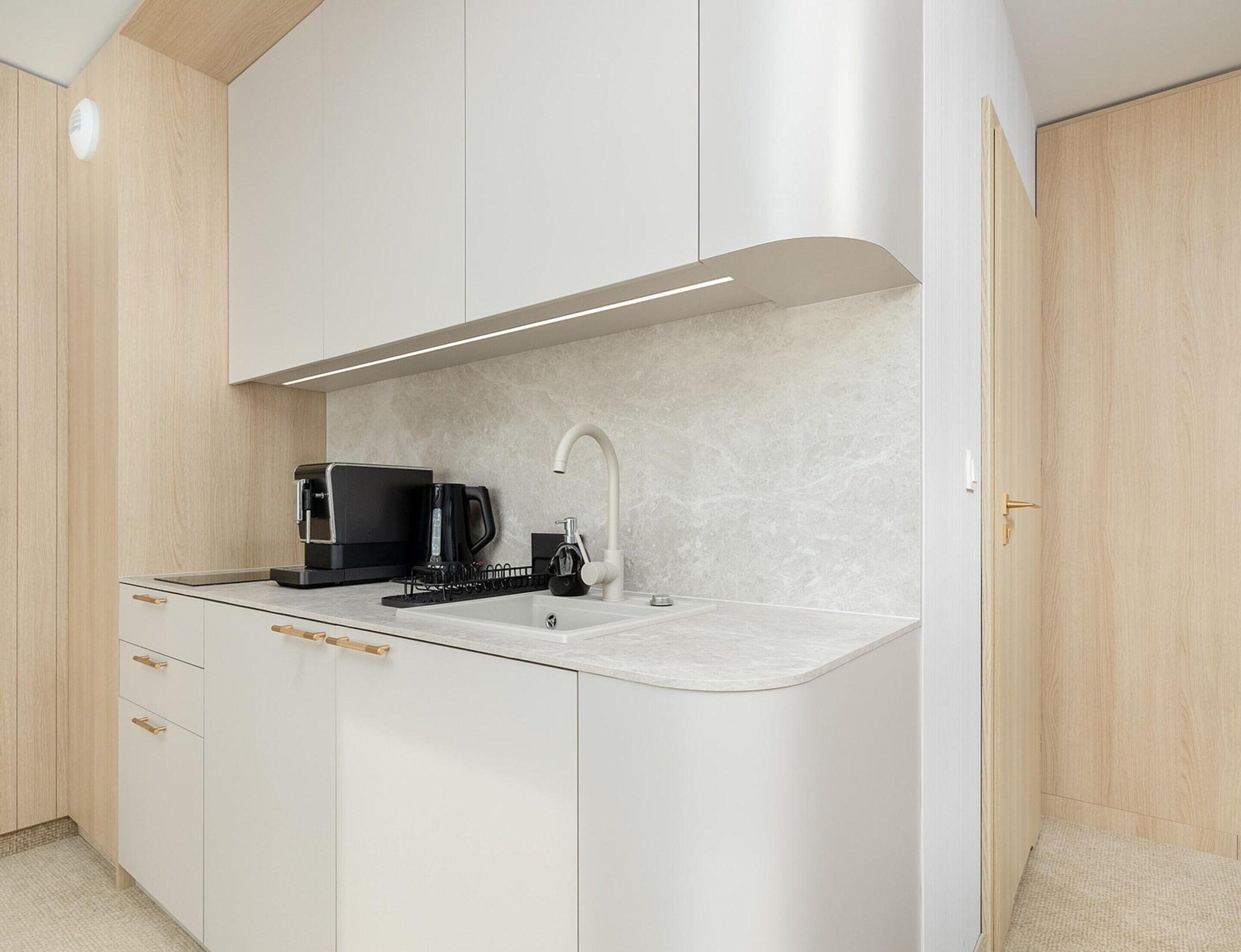 Cocina compacta con cafetera integrada, un lavamanos y una encimera.