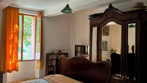 Un dormitorio con cama, armario, espejo y ventana con cortinas.