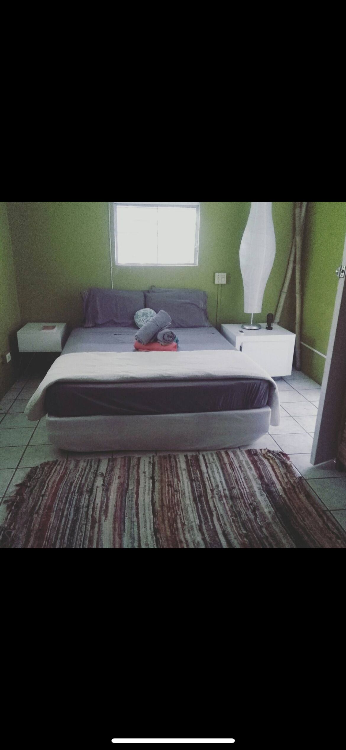 Un dormitorio con cama, mesita de noche y ventana.
