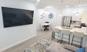 Une cuisine moderne dotée d’un grand îlot central, de meubles blancs et d’un éclairage suspendu.