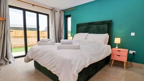A bedroom with a large bed, a nightstand, and a view of the outdoors.