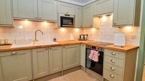 A kitchen with light green cabinets, a microwave, a toaster, and a sink.