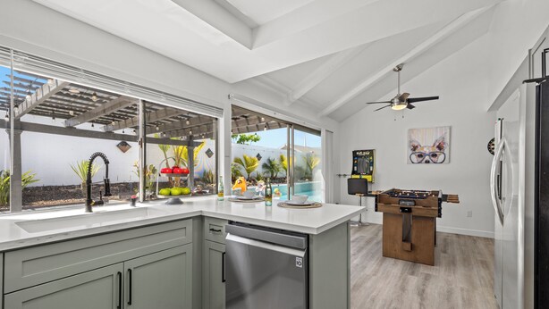 Una cocina moderna con lavavajillas, mesa de fútbol y un amplio ventanal con vistas a un jardín.