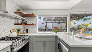 Una cocina moderna con estufa integrada, armarios grises y estantes de madera.