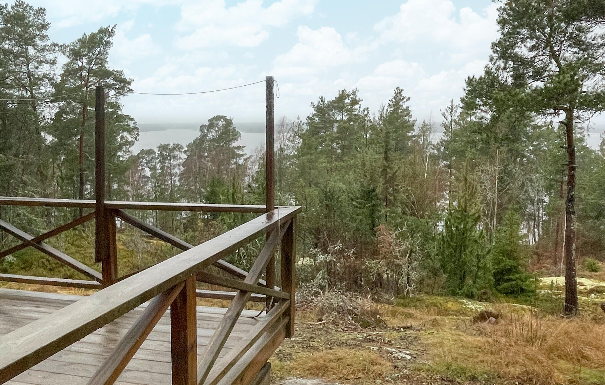 A wooden deck with a metal railing overlooking a forested area.