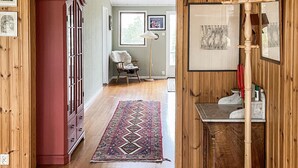 A hallway with a wooden floor, a red cabinet, a patterned rug, and a chair with a fur throw. - 3 bedroom amazing home in Yxlan (Yxlan)