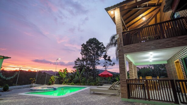 Un immeuble de deux étages doté d’un balcon, d’une piscine et offrant une vue sur le coucher de soleil.