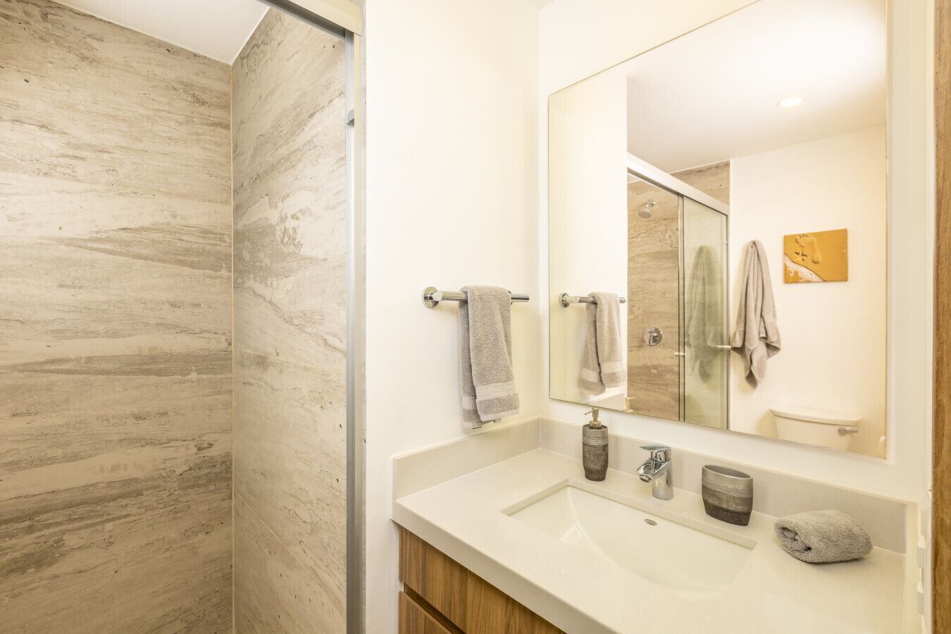 A modern bathroom with a large mirror, a sink, and a shower.
