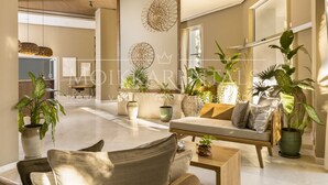 A spacious living room with a sofa, coffee table, and potted plants. - Wake Up to Paradise – Stunning 2BR Condo Right on the Beach (Puerto Vallarta)