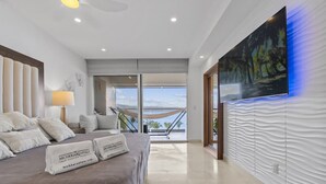 A modern hotel room with a large bed, a TV, and a balcony with a view. - Oceanfront Luxury + FREE Daily Breakfast Harbor171 (Puerto Vallarta)