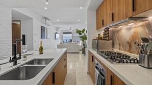 A modern kitchen with a central island, stainless steel appliances, and wooden cabinetry. - Oceanfront Luxury + FREE Daily Breakfast Harbor171 (Puerto Vallarta)