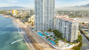 A high-rise hotel with multiple balconies, a beachside location, and a pool area. - Oceanfront Luxury + FREE Daily Breakfast Harbor171 (Puerto Vallarta)