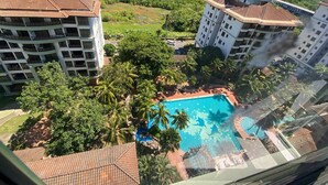 Ein Resort mit einem Swimmingpool, umgeben von üppiger Vegetation und Palmen.