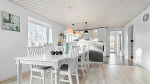 A spacious kitchen with white cabinetry, a central island, pendant lighting, and a view of the outdoors through large windows.