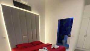 A modern bedroom with a large bed, white walls, and a blue accent wall. - Villa Bijou in Abidjan (Abidjan)