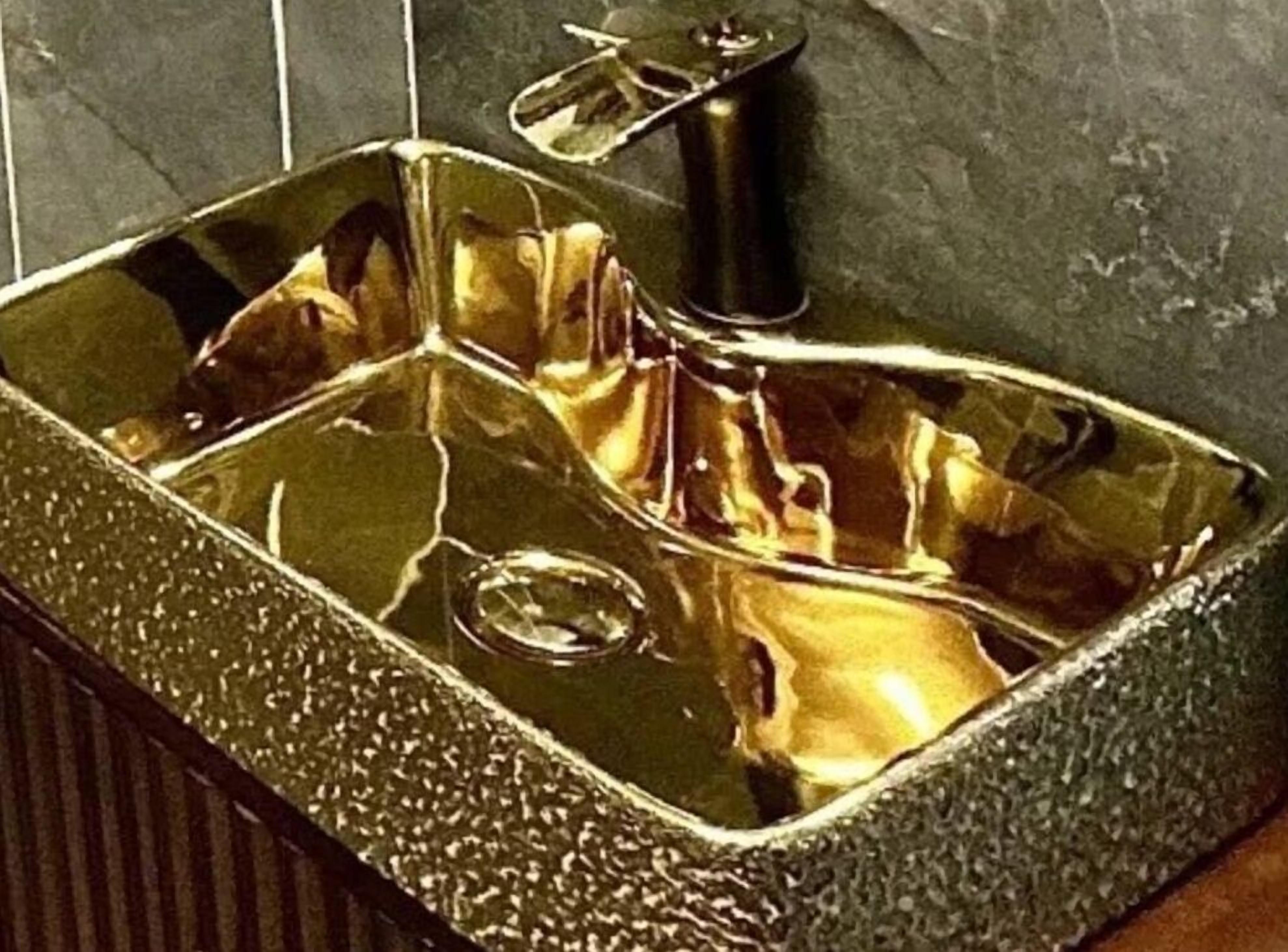 Ein rechteckiges, metallenes Waschbecken mit strukturierter Oberfläche und einem Wasserhahn.