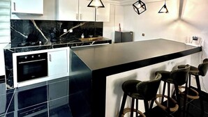 A modern kitchen with a central island, bar stools, and pendant lighting. - Villa Bijou in Abidjan (Abidjan)