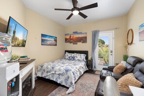 A bedroom with a bed, a ceiling fan, a water dispenser, a couch, and a door leading to a balcony. - Private Guest Suite  - Pool, Hot Tub, Cabana, Courtyard & Putting Green (Peoria)